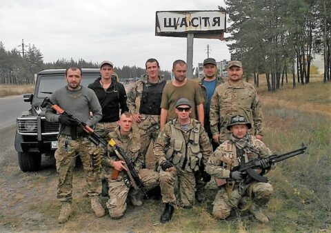 Kolorowa fotografia grupy żołnierzy ukraińskiego batalionu szturmowego „Ajdar” przy wjeździe do miasta Szczastia, gdzie jednostka chroniła porządek publiczny podczas wyborów prezydenckich w maju 2014 roku