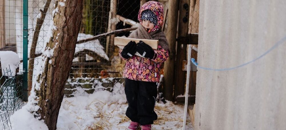 © UNICEF/Dmitrij Bortkiewicz Czteroletnia dziewczynka niesie drewno na opał do pieca w pobliżu swojego domu w obwodzie kijowskim na Ukrainie.
